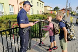 Policjant wyjaśnia chłopcom działanie odblasku po zmroku