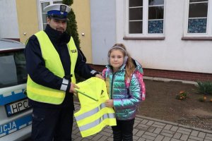 Policjant przekazuje dziewczynce kamizelkę