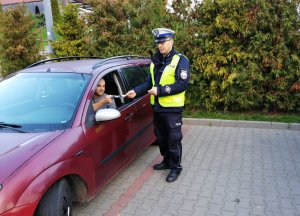 Policjant wręcza ulotkę kierowcy
