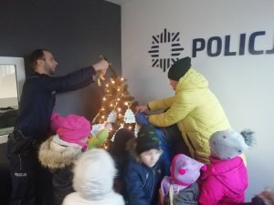 dekorowanie choinki przez policjanta z dziećmi