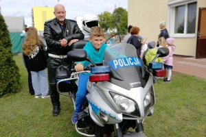 Chłopiec siedzi za kierownicą motocykla, obok stoi policjant