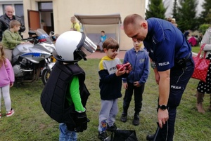 Policjant pomaga dziecku obrać ochraniacze i hełm
