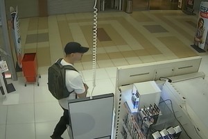 Mężczyzna w czapce z plecakiem na ramionach wychodzi ze sklepu