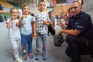 troje dzieci wraz z policjantem pozuje do zdjęcia, trzymają w rękach odblaski