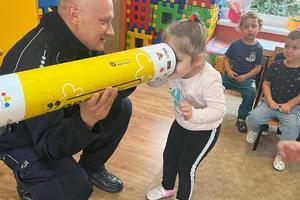 Policjant pokazuje dziecku zasadę działania odblasków
