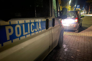 Policyjny radiowóz stoi za kontrolowaną osobówką