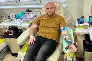 Mężczyzna uśmiecha się do zdjęcia, oddaje krew dla potrzebujących