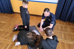 Policjant kontroluje umiejętności uczniów z pierwszej pomocy